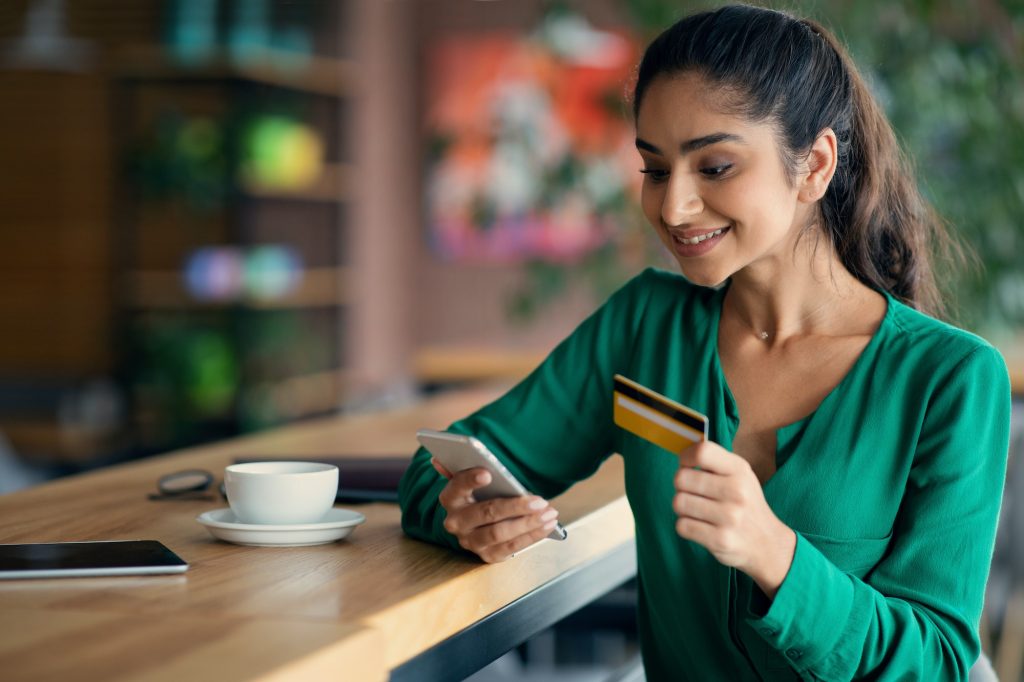 Happy young lady using mobile phone and credit card